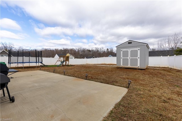 view of patio with a fenced backyard, an outbuilding, a trampoline, a storage unit, and a playground