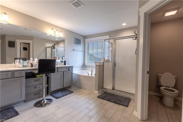 bathroom with visible vents, vanity, a garden tub, wood finish floors, and a shower stall