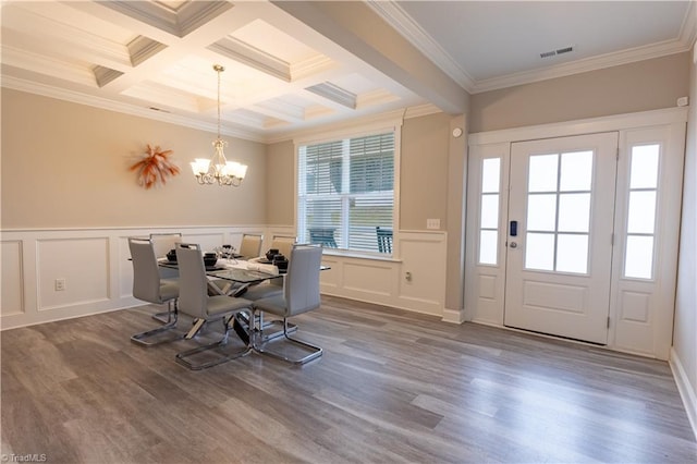 dining space with a chandelier, beamed ceiling, wood finished floors, and visible vents