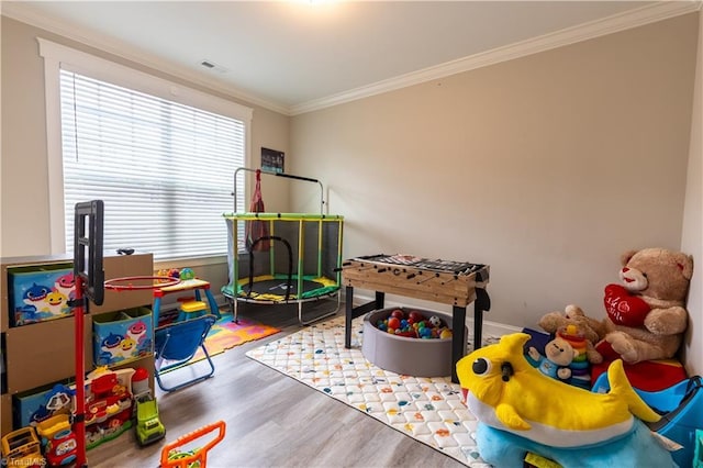 playroom with ornamental molding, wood finished floors, visible vents, and baseboards