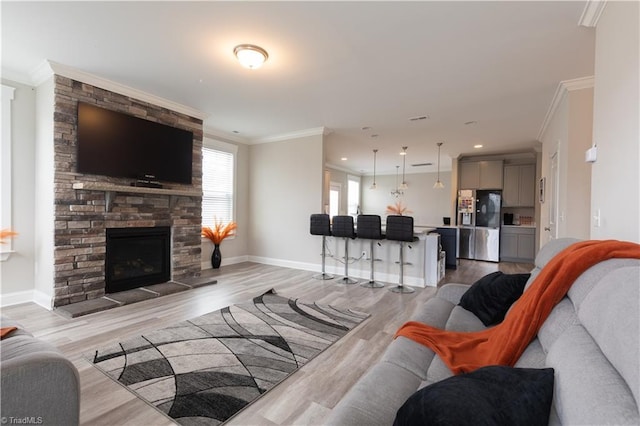 living area with a fireplace, recessed lighting, ornamental molding, light wood-type flooring, and baseboards