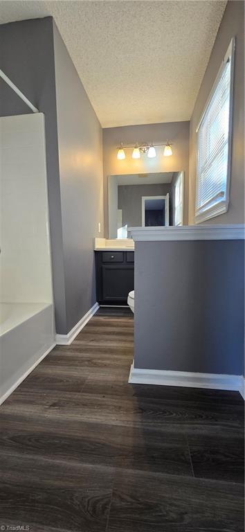 full bathroom with a textured ceiling, vanity, toilet, and hardwood / wood-style floors