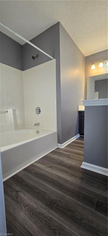 bathroom with bathing tub / shower combination, hardwood / wood-style floors, vanity, and a textured ceiling