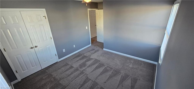 unfurnished bedroom with dark carpet and a closet