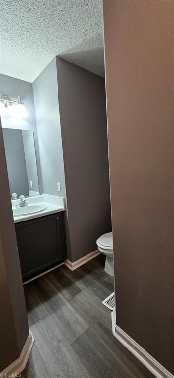 bathroom with hardwood / wood-style floors, vanity, a textured ceiling, and toilet