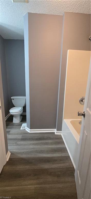 bathroom with toilet, wood-type flooring, and a textured ceiling