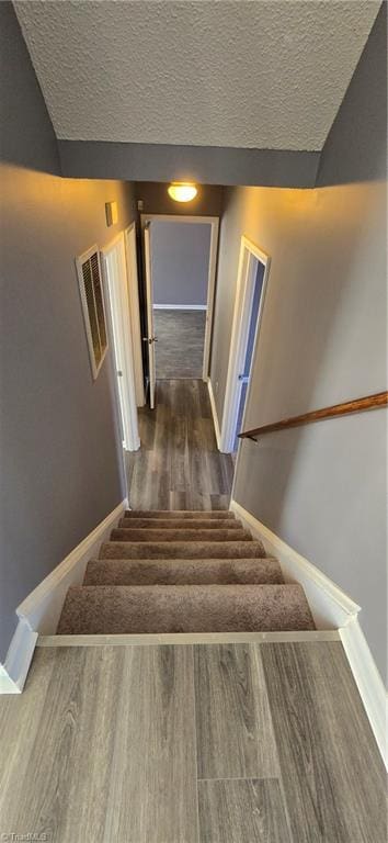 staircase featuring hardwood / wood-style floors and a textured ceiling