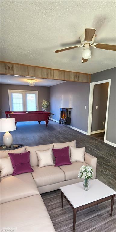 living room with a wood stove, billiards, ceiling fan, dark hardwood / wood-style floors, and a textured ceiling