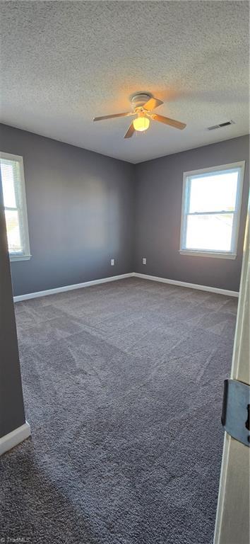 carpeted spare room featuring ceiling fan and a textured ceiling