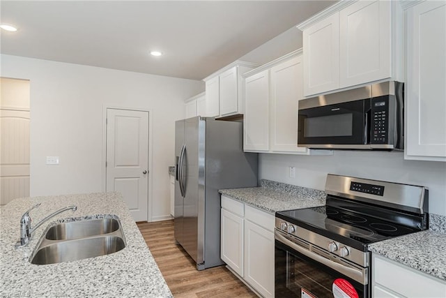 kitchen featuring stainless steel appliances, light stone countertops, sink, and white cabinets