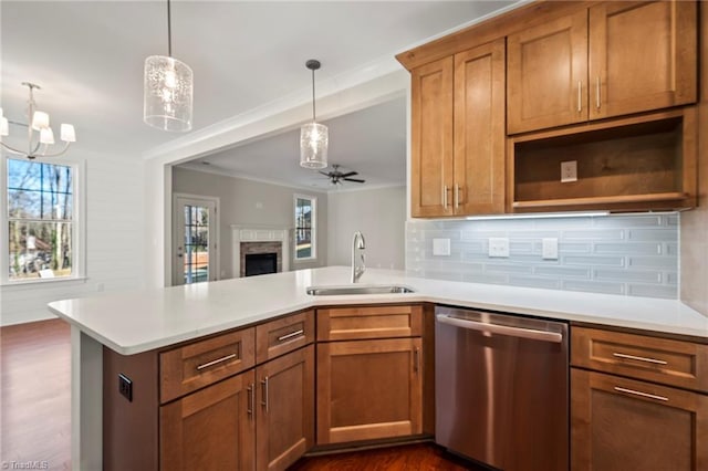 kitchen featuring light countertops, a sink, decorative light fixtures, and stainless steel dishwasher