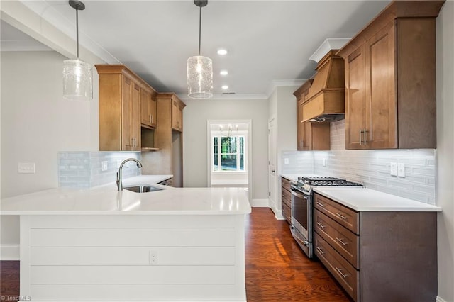 kitchen with stainless steel gas stove, custom range hood, light countertops, and decorative light fixtures