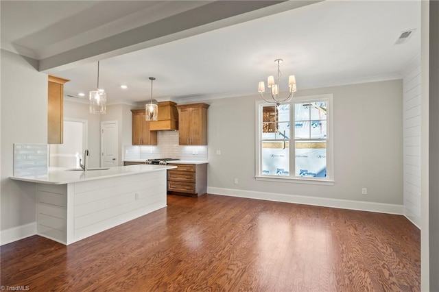 kitchen with a sink, brown cabinets, pendant lighting, and light countertops