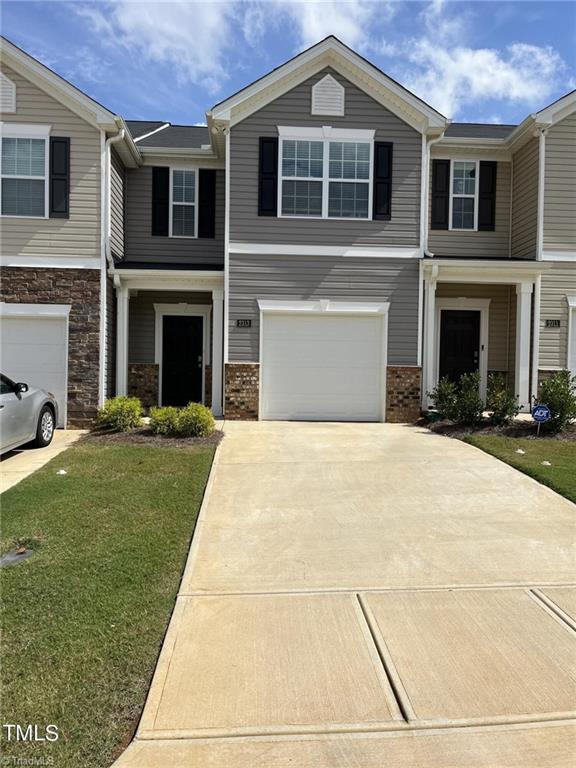 view of property with a front lawn, brick siding, driveway, and an attached garage