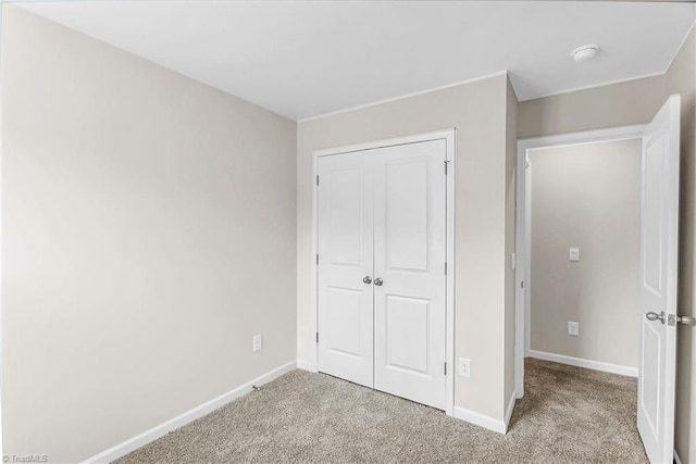 unfurnished bedroom featuring baseboards, a closet, and light colored carpet