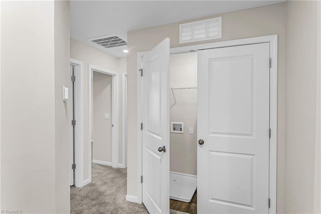 hallway featuring carpet flooring, visible vents, and baseboards