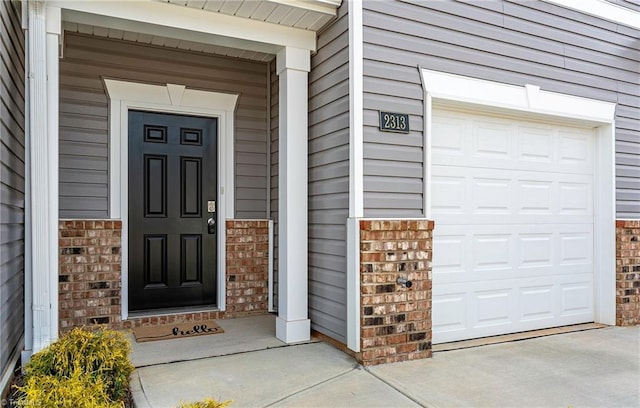 property entrance with a garage and brick siding