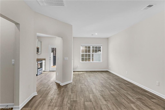 spare room with baseboards, visible vents, and wood finished floors