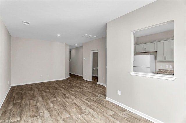 unfurnished room featuring recessed lighting, wood finished floors, visible vents, and baseboards