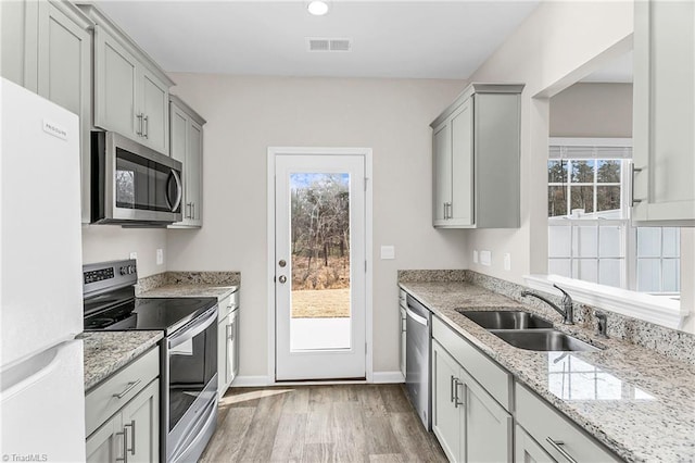 kitchen with light wood-style flooring, appliances with stainless steel finishes, a sink, and gray cabinetry