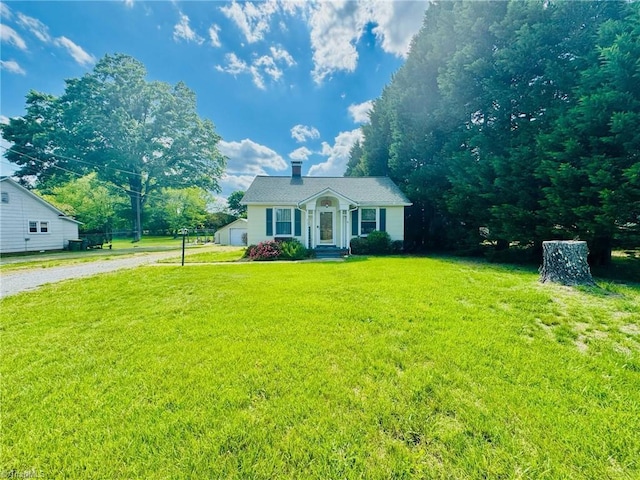 view of front of property with a front yard, a chimney, and driveway