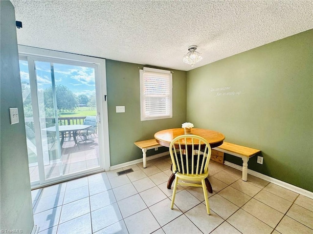 dining room featuring breakfast area, plenty of natural light, a textured ceiling, baseboards, and light tile patterned flooring