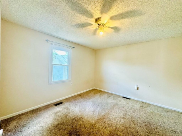empty room with a textured ceiling, carpet flooring, a ceiling fan, and baseboards