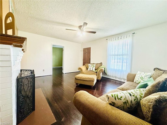 living room with wood-type flooring, ceiling fan, a fireplace, a textured ceiling, and baseboards