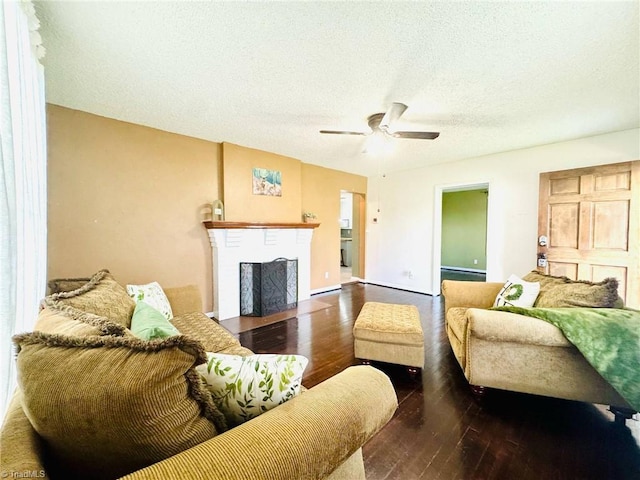 living area with hardwood / wood-style flooring, ceiling fan, a fireplace with flush hearth, and a textured ceiling