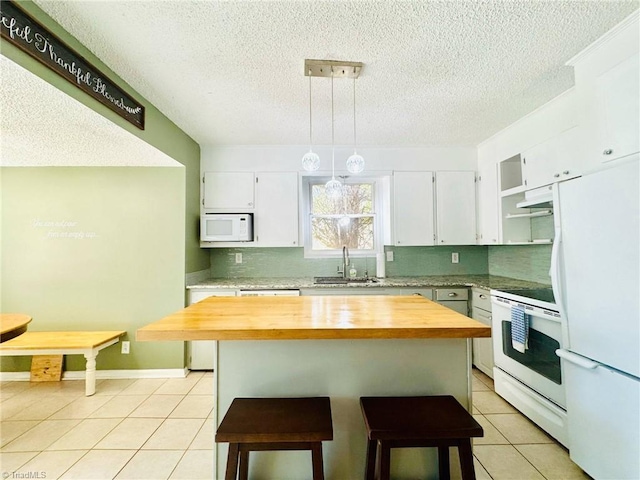 kitchen featuring wood counters, white appliances, a sink, light tile patterned flooring, and a textured ceiling