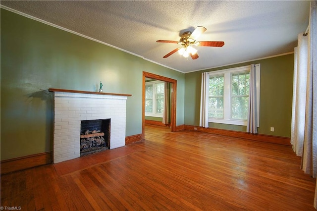 unfurnished living room with hardwood / wood-style floors, ceiling fan, a textured ceiling, ornamental molding, and a fireplace