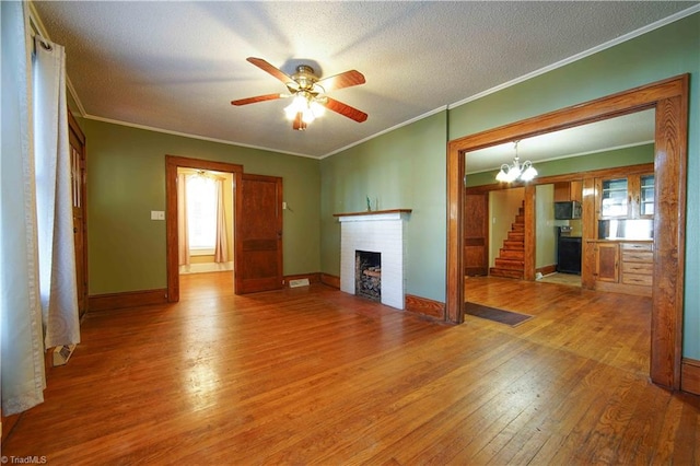 unfurnished living room featuring a healthy amount of sunlight, hardwood / wood-style flooring, a textured ceiling, and ceiling fan with notable chandelier