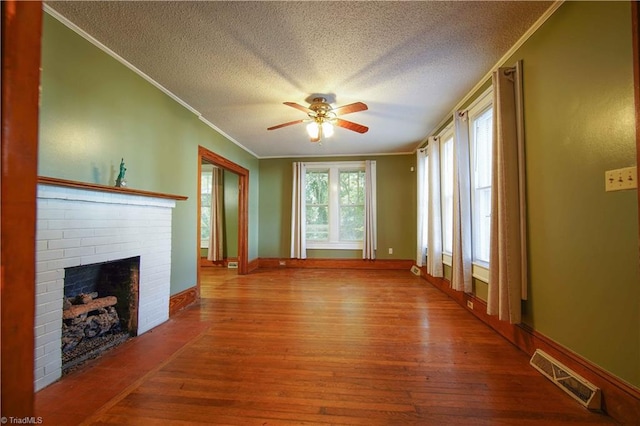 unfurnished living room featuring hardwood / wood-style flooring, a textured ceiling, ornamental molding, and a fireplace