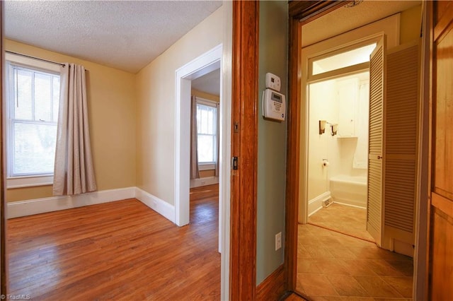 corridor featuring a textured ceiling and light wood-type flooring