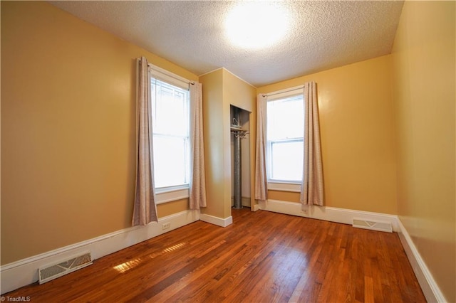 unfurnished room with dark wood-type flooring and a textured ceiling