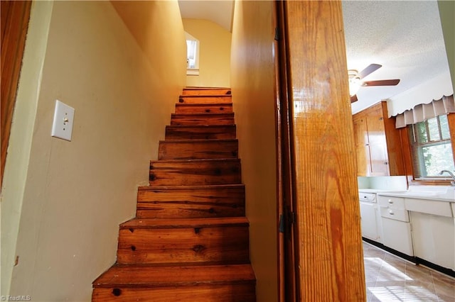 stairway featuring ceiling fan, a textured ceiling, and sink