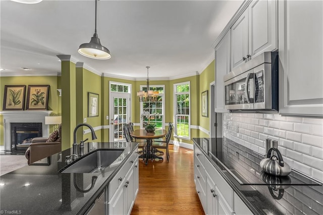 3116 Lodge Dr, Jamestown, NC 27282 - kitchen featuring stainless steel microwave, a sink, a premium fireplace, decorative backsplash, and dark stone countertops