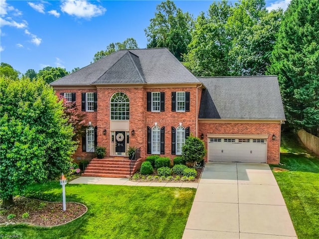 3116 Lodge Dr, Jamestown, NC 27282 - georgian-style home featuring brick siding, a front yard, driveway, and roof with shingles