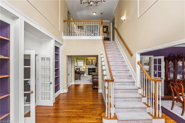 3116 Lodge Dr, Jamestown, NC 27282 - stairs featuring a towering ceiling, french doors, wood finished floors, a chandelier, and crown molding