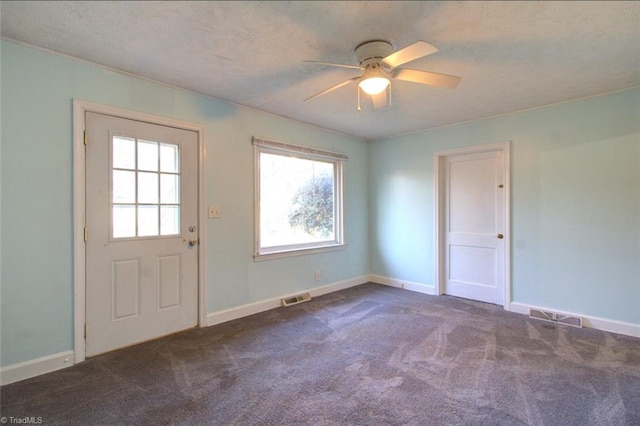 interior space featuring ceiling fan, a textured ceiling, visible vents, baseboards, and carpet