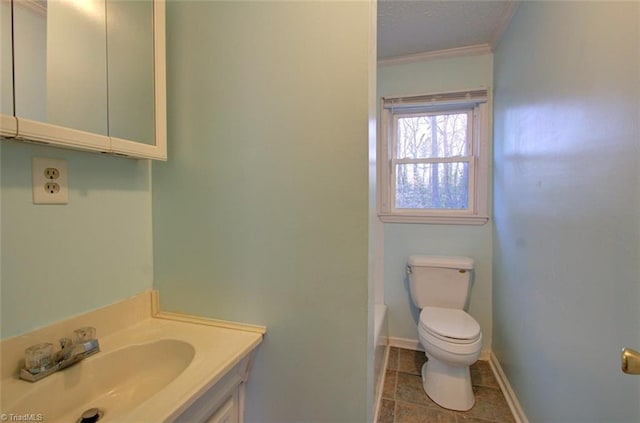 bathroom featuring vanity, toilet, a tub, baseboards, and ornamental molding