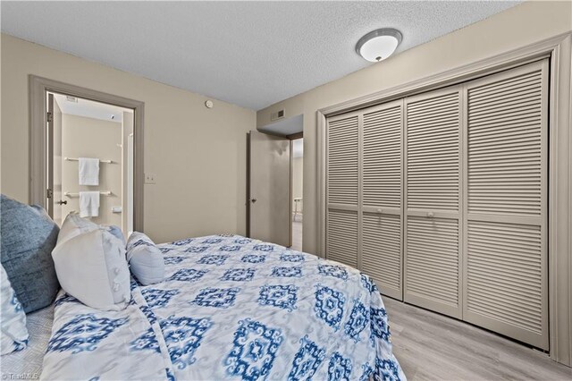 bedroom featuring a closet, light wood-type flooring, and a textured ceiling