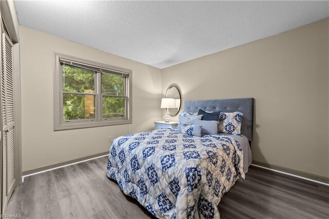 bedroom featuring a textured ceiling, dark hardwood / wood-style floors, and a closet