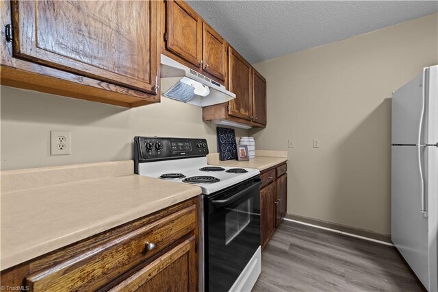 kitchen featuring hardwood / wood-style flooring, a textured ceiling, and white appliances