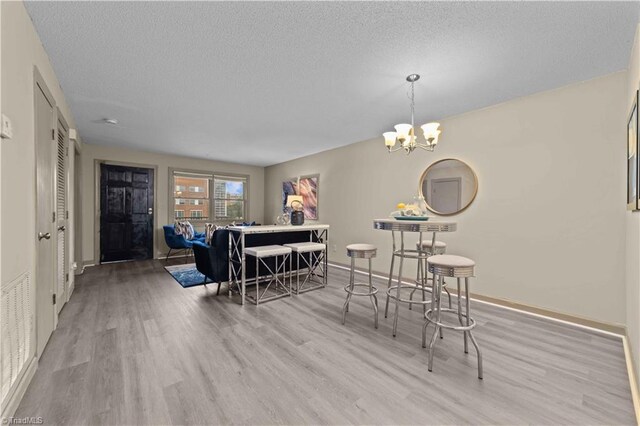 dining area with a textured ceiling, light hardwood / wood-style flooring, and a chandelier