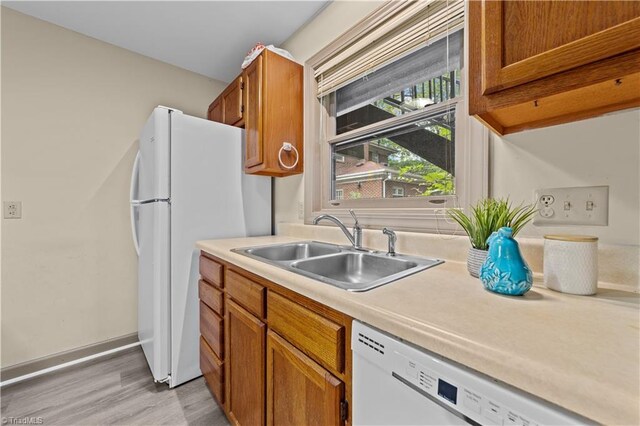 kitchen featuring light wood-type flooring, white appliances, and sink