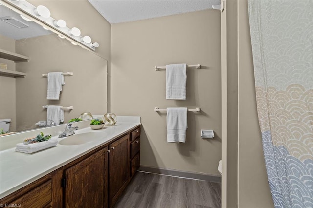 bathroom featuring a textured ceiling, vanity, toilet, and hardwood / wood-style flooring