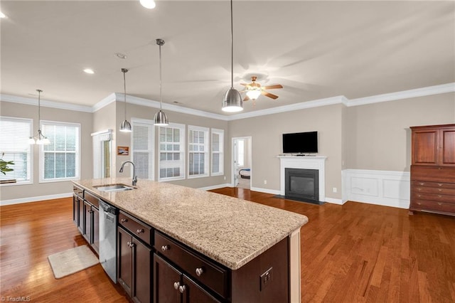 kitchen with hanging light fixtures, light stone counters, hardwood / wood-style flooring, crown molding, and sink