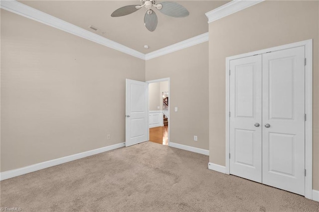 unfurnished bedroom featuring a closet, ceiling fan, crown molding, and light colored carpet