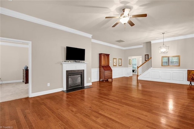 unfurnished living room with ornamental molding, hardwood / wood-style floors, and ceiling fan with notable chandelier